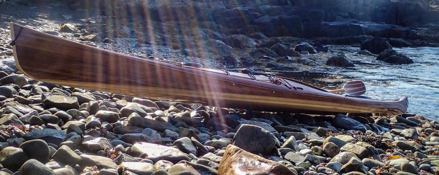 wooden sea kayak on rugged shore